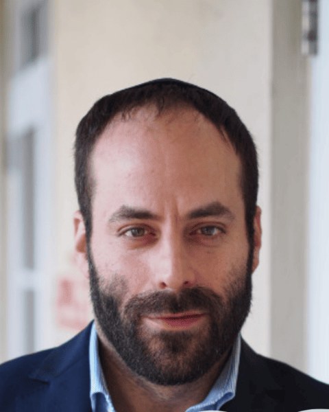 Eliezer Nerenberg, photographed in a doorway in a dark jacket.